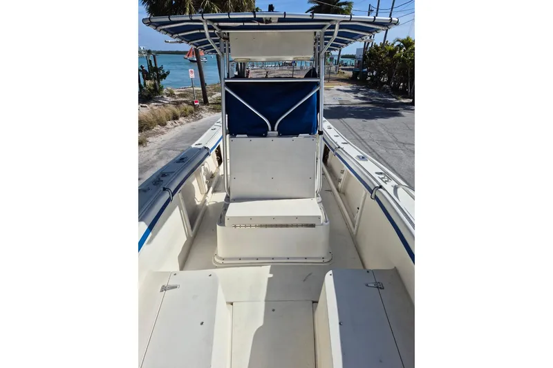 Slide: The Image of 1987 Mako 261 Center Console boat with blue canopy, docked near the ocean. - 35