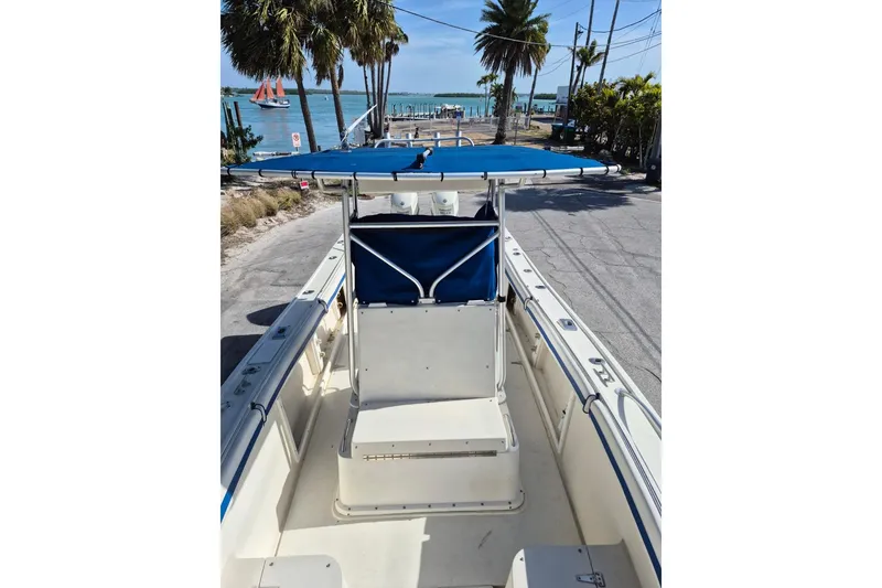 Slide: The Image of 1987 Mako 261 Center Console boat with blue canopy, parked near a scenic waterfront. - 36