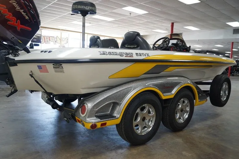Slide: The Image of 2006 Ranger 521 VX boat with yellow accents on a dual-axle trailer in showroom. - 18
