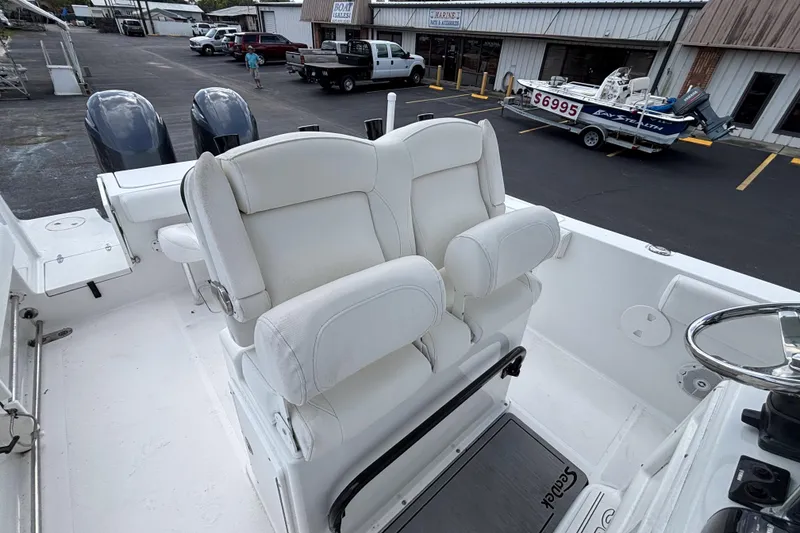 Slide: The Image of 2018 Sea Hunt Gamefish 27 boat with dual seats and steering wheel, parked outdoors. - 27
