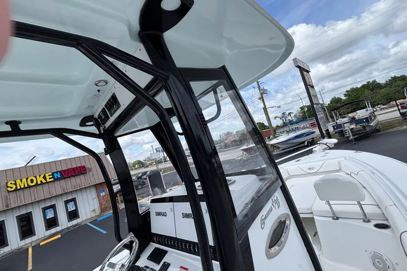 Slide: The Image of 2018 Sea Hunt Gamefish 27 boat near a Smoke N Vape store, showcasing helm and seating. - 30