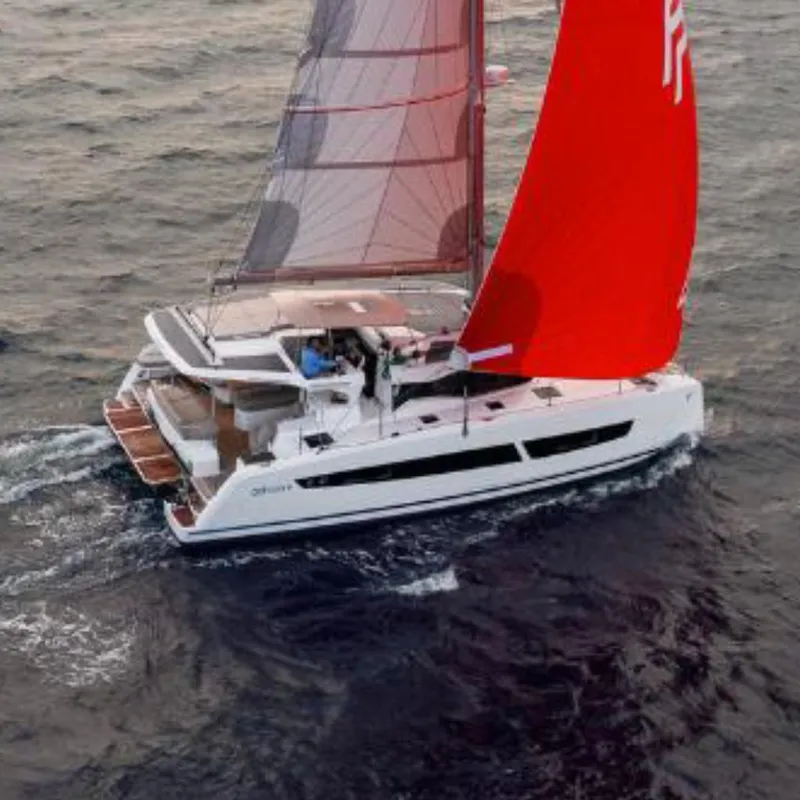 Slide: The Image of 2025 Fountaine Pajot NEW 41 catamaran sailing at sunset with vibrant red sails. - 2