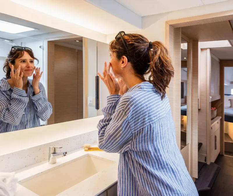 Slide: The Image of Woman in striped shirt applying skincare in Fountaine Pajot NEW 41 yacht bathroom, 2025 model. - 28