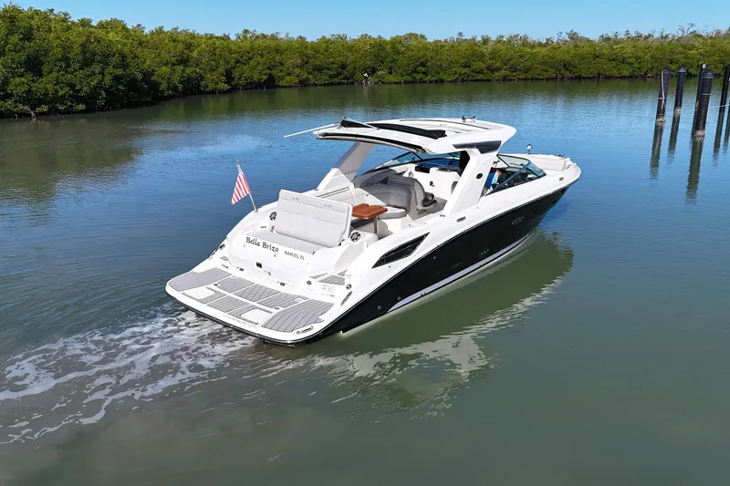 Slide: The Image of 2023 Sea Ray SLX 350 boat cruising on calm water with lush greenery. - 2