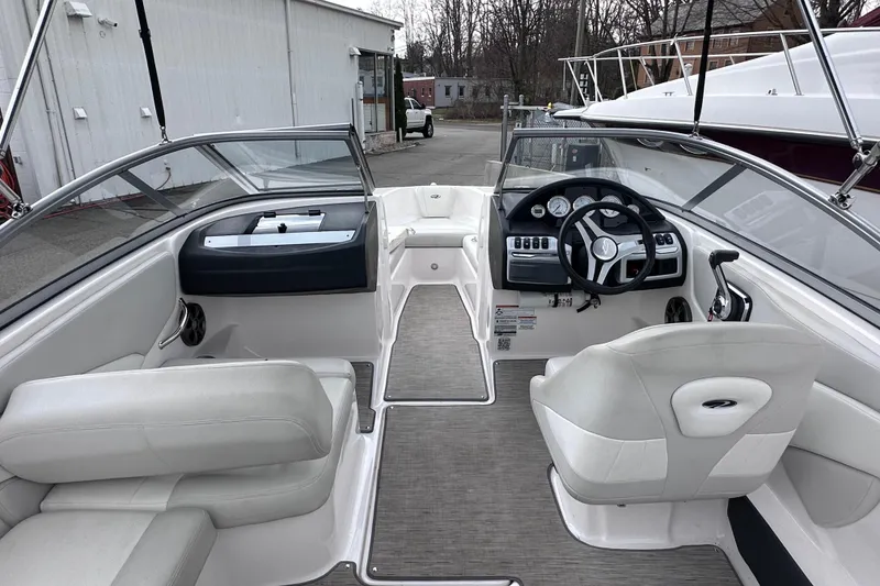 Slide: The Image of 2018 Regal 1900 ES Bowrider interior with steering wheel and seating, docked outdoors. - 12