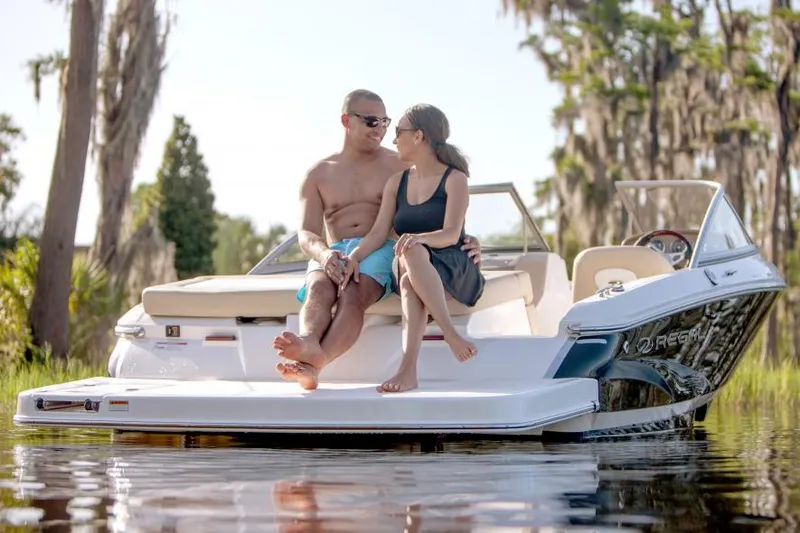 Slide: The Image of Manufacturer Provided Image: Couple relaxing on a 2018 Regal 1900 ES Bowrider boat in a serene lake. - 26