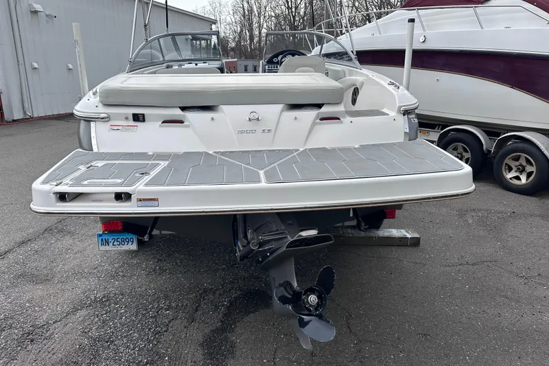 Slide: The Image of 2018 Regal 1900 ES Bowrider boat, rear view, parked on pavement near other boats. - 4