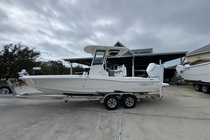 The Image of 2026 Caymas 26 HB boat on trailer, parked outdoors under cloudy sky. - 1