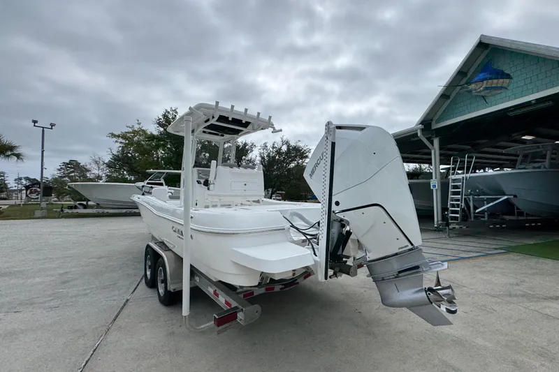 Slide: The Image of 2026 Caymas 26 HB boat on trailer, parked outdoors near a boathouse. - 14