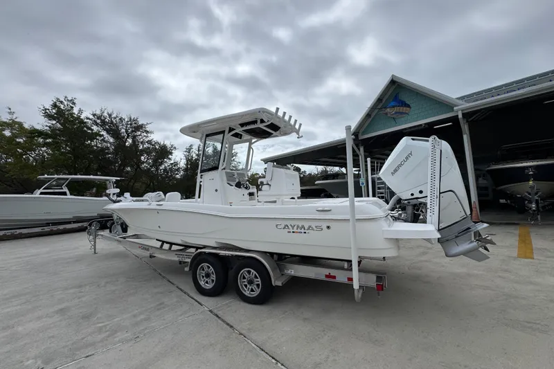 Slide: The Image of 2026 Caymas 26 HB boat on trailer, parked outside a showroom under cloudy skies. - 16