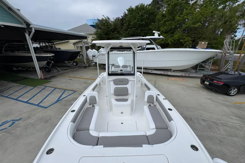 Slide: The Image of 2026 Caymas 26 HB boat with spacious seating, parked outdoors near other boats. - 22