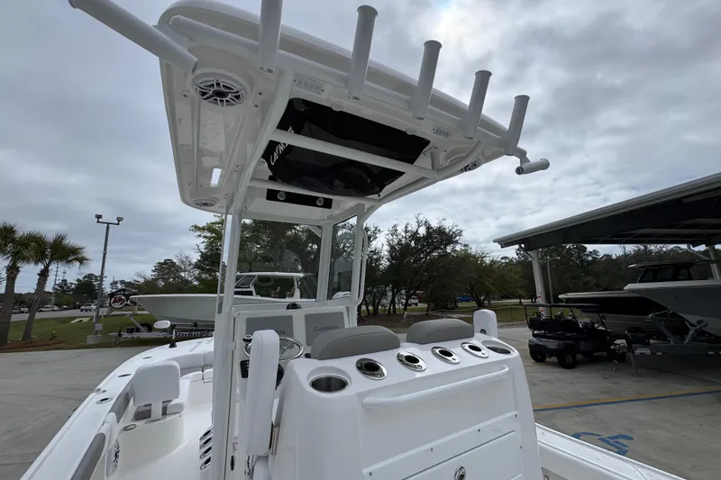 Slide: The Image of 2026 Caymas 26 HB boat with T-top and rod holders, parked outdoors. - 36