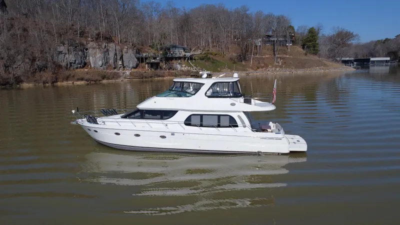 Slide: The Image of 2005 Carver 56 Voyager yacht on a calm lake with wooded shoreline. - 1