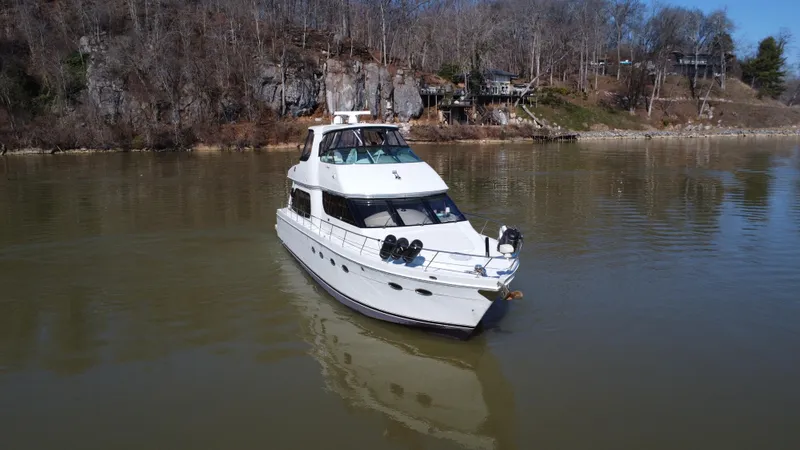 Slide: The Image of 2005 Carver 56 Voyager yacht on calm river with wooded shoreline. - 3