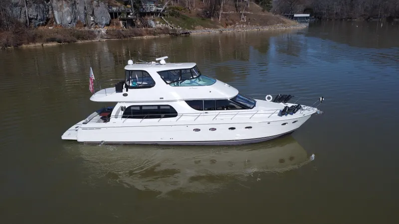 Slide: The Image of 2005 Carver 56 Voyager yacht on a calm lake, surrounded by rocky shoreline. - 4