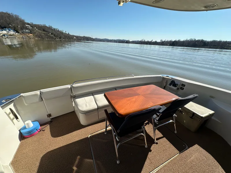 Slide: The Image of 2005 Carver 56 Voyager yacht deck with table and chairs overlooking calm river. - 7
