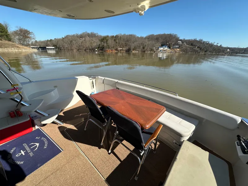 Slide: The Image of 2005 Carver 56 Voyager yacht deck with table, chairs, and scenic lake view. - 8