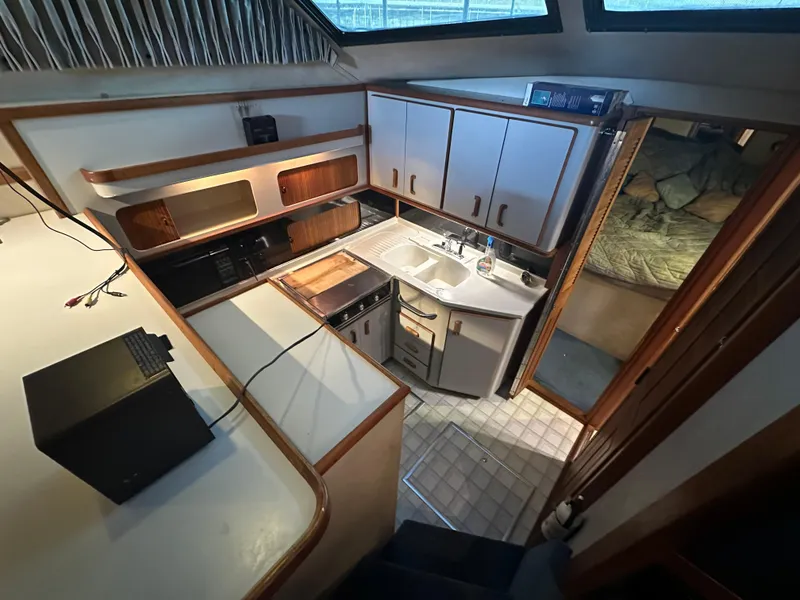 Slide: The Image of 1991 Sea Ray 380 Aft Cabin kitchen area with sink, stove, and cabinets. - 11