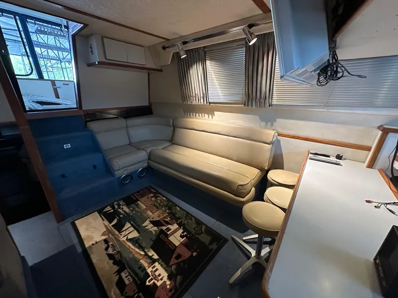 Slide: The Image of 1991 Sea Ray 380 Aft Cabin interior with beige seating, bar stools, and a colorful rug. - 9