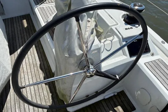 Slide: The Image of Steering wheel of a 2017 Beneteau Oceanis 41.1 sailboat, featuring teak decking and navigation equipment. - 16