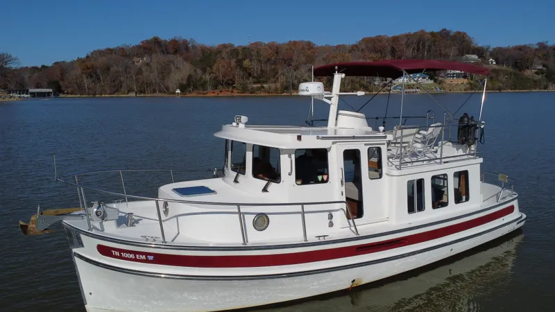 The Image of 2007 Nordic Tug 32 boat on calm lake with wooded shoreline. - 0