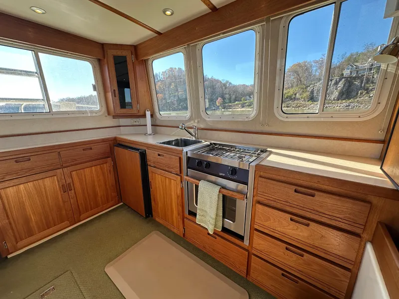 Slide: The Image of 2007 Nordic Tug 32 interior kitchen with wooden cabinets and large windows. - 14