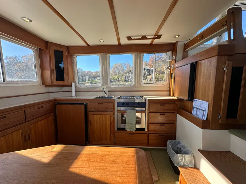 Slide: The Image of Interior of 2007 Nordic Tug 32, featuring a cozy kitchen with wooden cabinetry and large windows. - 16