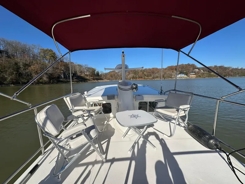 Slide: The Image of 2007 Nordic Tug 32 boat deck with chairs and table under red canopy on calm water. - 19