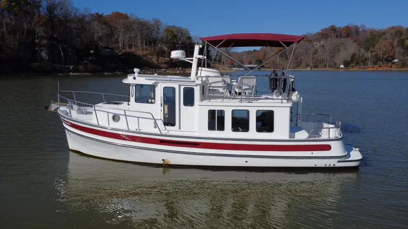 Slide: The Image of 2007 Nordic Tug 32 boat on calm lake with scenic background. - 2