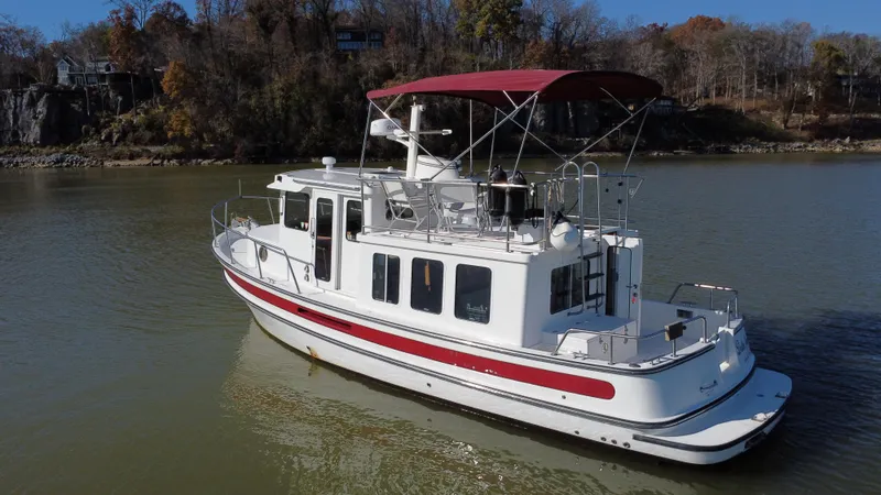 Slide: The Image of 2007 Nordic Tug 32 cruising on a calm river with scenic autumn backdrop. - 3