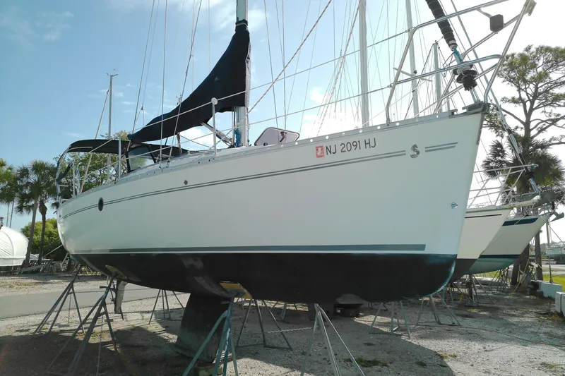 Slide: The Image of 1993 Beneteau First 310 sailboat on stands, ready for maintenance under a clear sky. - 1