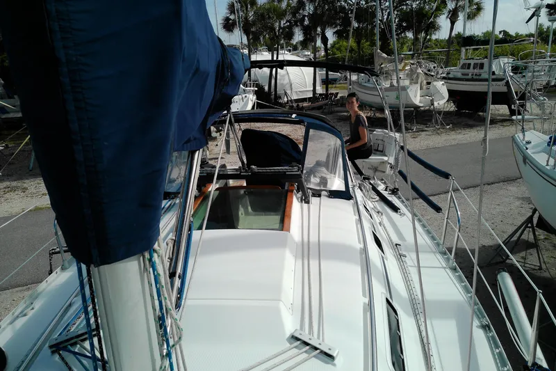 Slide: The Image of 1993 Beneteau First 310 sailboat docked, featuring blue sails and deck details. - 12