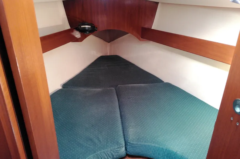 Slide: The Image of 1993 Beneteau First 310 cabin interior with green cushions and wooden accents. - 28