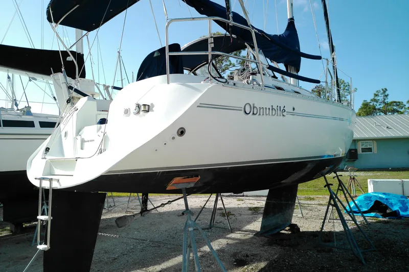 Slide: The Image of 1993 Beneteau First 310 sailboat on stands, named "Obnubilé," in a boatyard setting. - 3