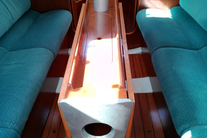 Slide: The Image of Interior of 1993 Beneteau First 310 sailboat with teal seating and wooden table. - 42