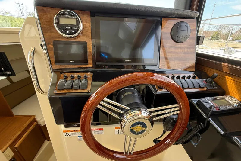 Slide: The Image of 2026 Ranger Tugs R-25 helm with wooden steering wheel and modern navigation controls. - 12