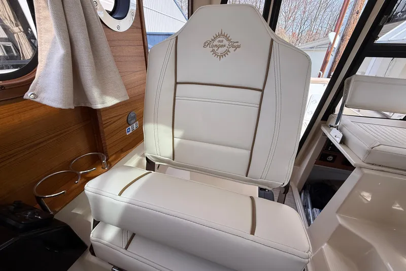 Slide: The Image of 2026 Ranger Tugs R-25 interior with elegant white seating and wood accents. - 14