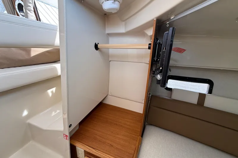 Slide: The Image of 2026 Ranger Tugs R-25 interior closet with wooden flooring and mounted TV. - 15