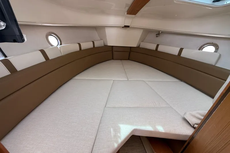Slide: The Image of Interior cabin of 2026 Ranger Tugs R-25 with cushioned seating and portholes. - 16