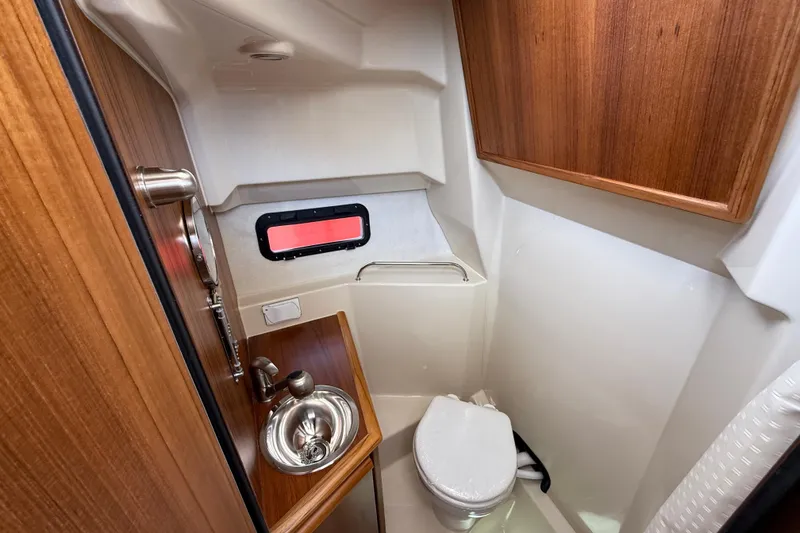 Slide: The Image of 2026 Ranger Tugs R-25 boat bathroom with wooden cabinetry and stainless steel sink. - 17