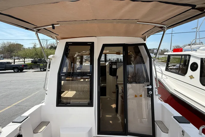 Slide: The Image of 2026 Ranger Tugs R-25 boat with open cabin door, showcasing interior and canopy. - 8