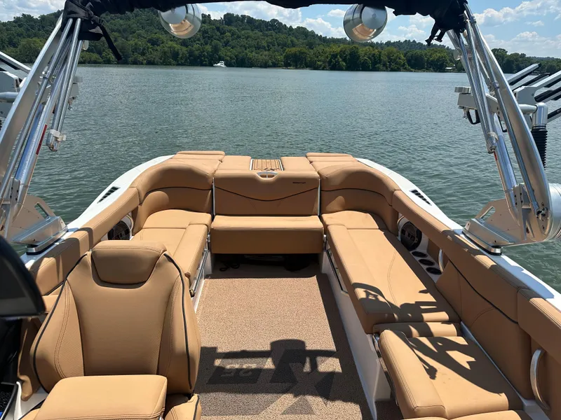 Slide: The Image of 2021 MasterCraft XT25 boat interior with tan seating on a lake. - 10