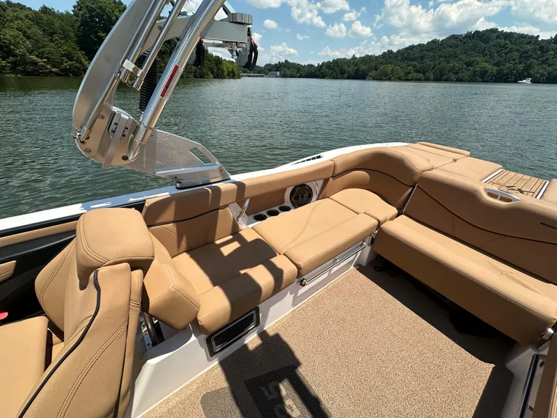 Slide: The Image of 2021 MasterCraft XT25 boat interior with tan seating on a lake. - 11