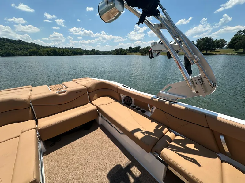 Slide: The Image of 2021 MasterCraft XT25 boat interior with tan seating on a lake. - 12