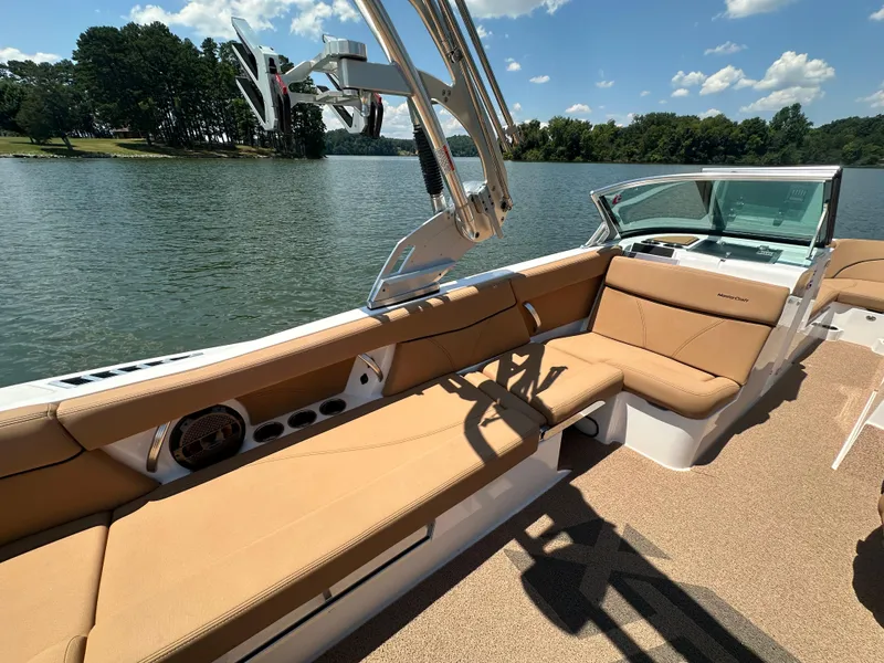 Slide: The Image of 2021 MasterCraft XT25 boat interior with tan seating on a sunny lake. - 14