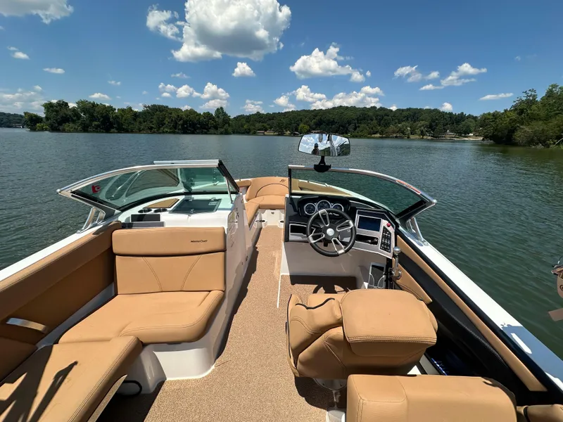 Slide: The Image of 2021 MasterCraft XT25 boat interior with tan seating on a lake. - 16