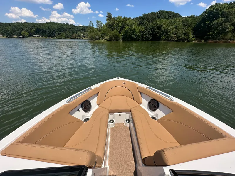 Slide: The Image of 2021 MasterCraft XT25 boat interior with tan seating on a lake. - 17