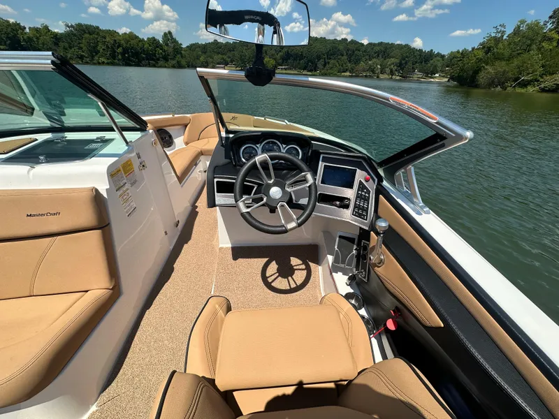 Slide: The Image of 2021 MasterCraft XT25 boat interior with steering wheel and dashboard on a lake. - 18