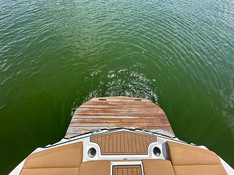 Slide: The Image of MasterCraft XT25 2021 boat stern with teak swim platform on green water. - 19