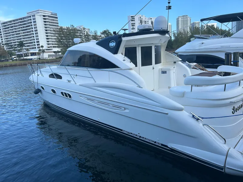 Slide: The Image of 2006 Neptunus 55 Cabrio yacht docked in marina, with modern buildings in background. - 2